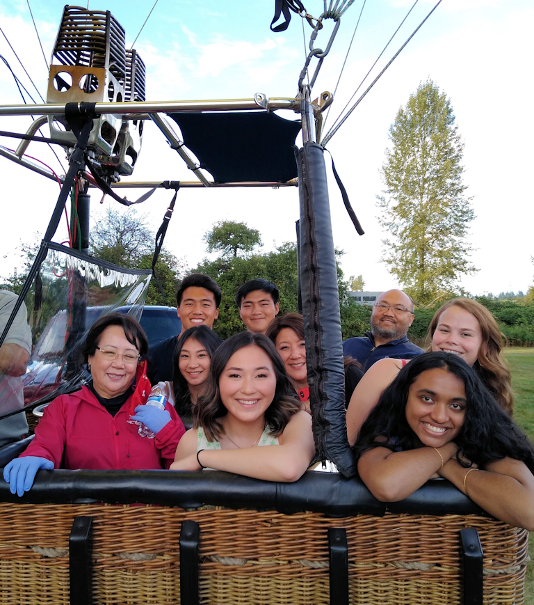 a group of happy people in a hot air balloon basket awaiting take off.