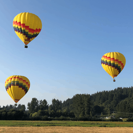 three hot air balloons just after take off on a blue sky day near Seattle Washington